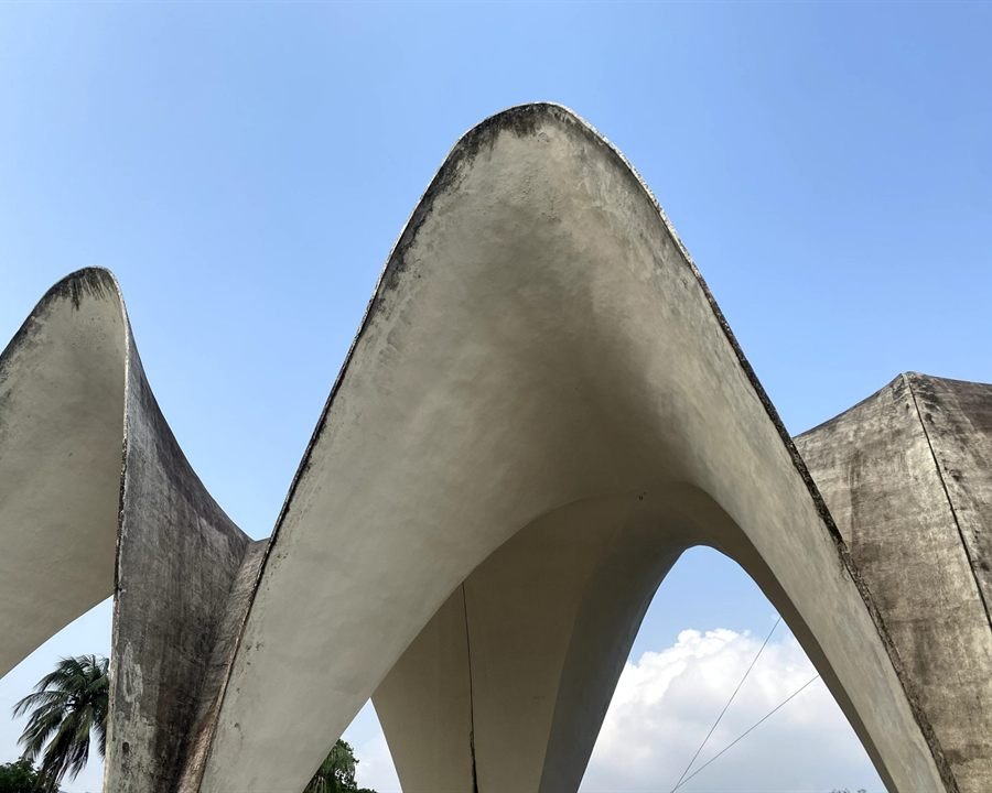 Concrete arches of a railway station concourse against a clear blue sky